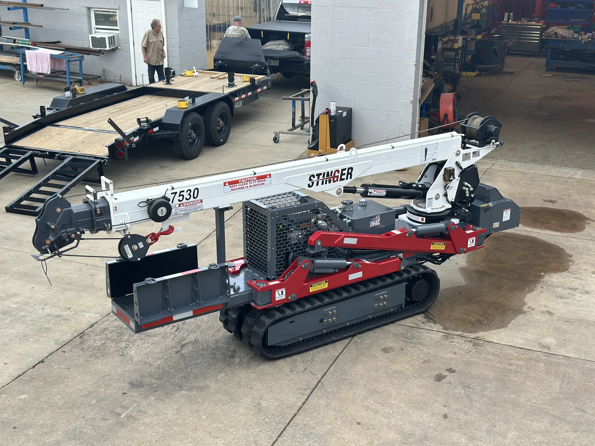 Custom compact tracked boom equipment in its stowed configuration at the workshop